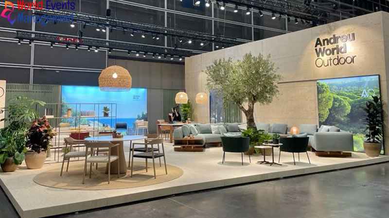 Modern white exhibition stand with open layout, digital displays, and comfortable visitor seating area