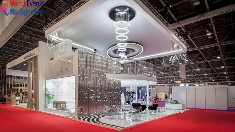 Modern exhibition stand in Dubai with glass walls, white interiors, circular lighting, and visitor seating