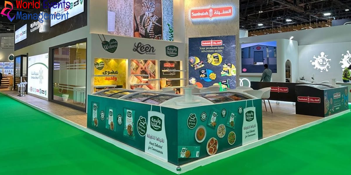 Custom exhibition stand with branded product displays and green carpet flooring at a trade show